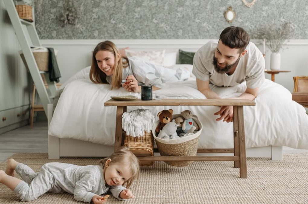 A joyful family bonding in a cozy bedroom, featuring a playful child and loving parents.