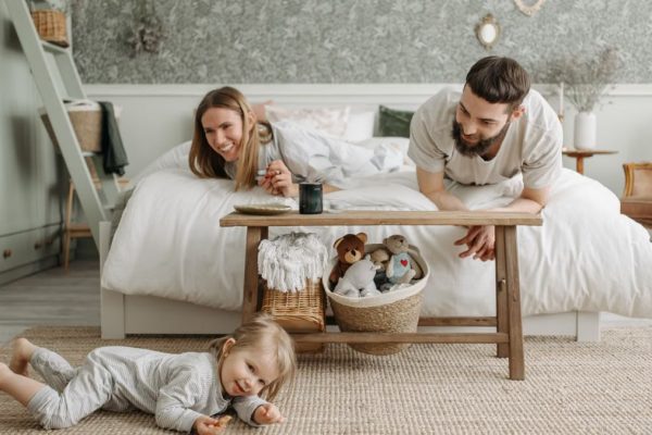 A joyful family bonding in a cozy bedroom, featuring a playful child and loving parents.