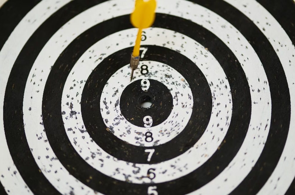 Close-up of a dart hitting the bullseye on a black and white target board symbolizing success.