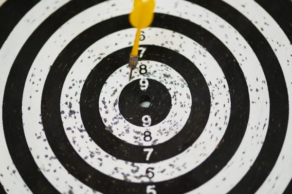 Close-up of a dart hitting the bullseye on a black and white target board symbolizing success.